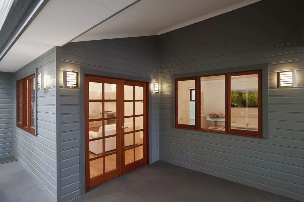 Exterior of a granny flat. showing windows, glass door with wooden frame and exterior of the dwelling