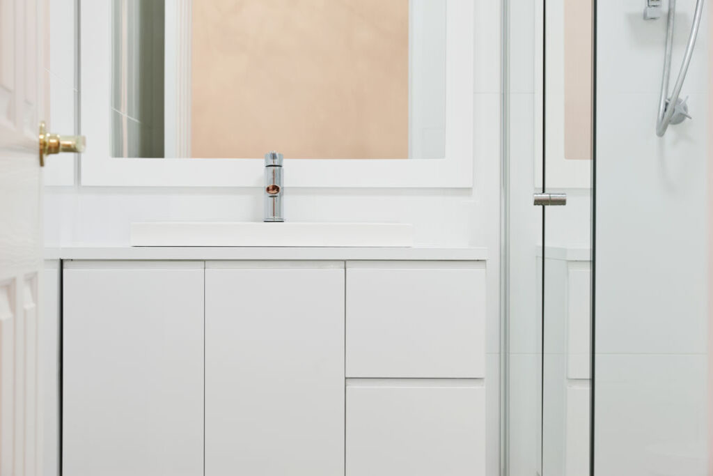 White bathroom sink with tap and mirror.