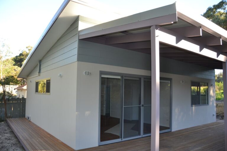 white granny flat with awning and sliding glass door