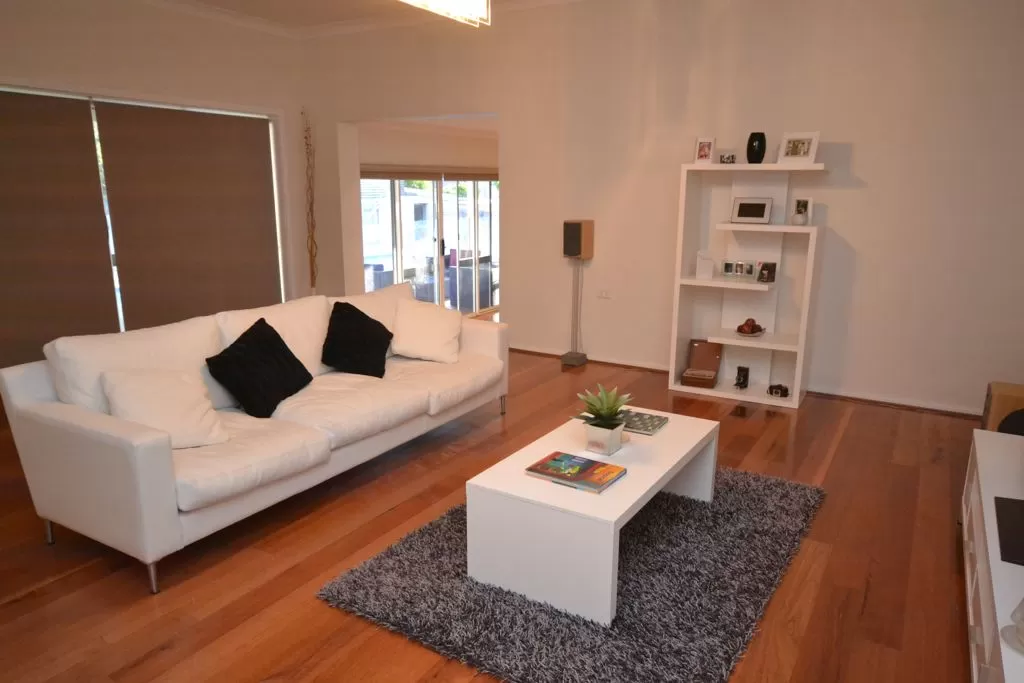 Living room with white couch, white coffee table, white shelving and a brown, hardwood floor