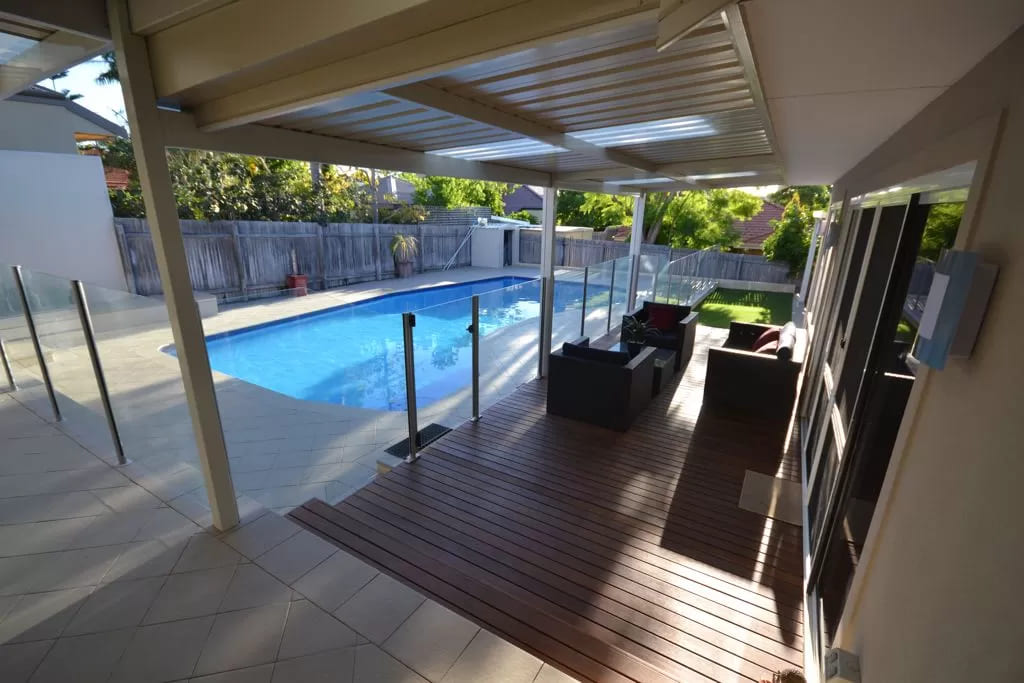 Backyard with wooden deck, outdoor furniture and swimming pool. 