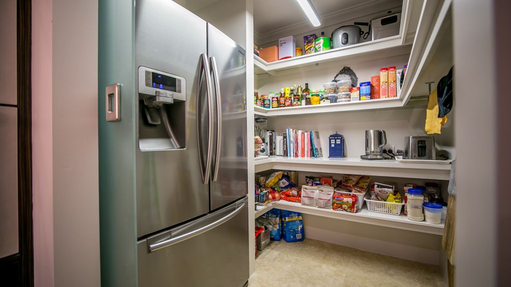 metallic refrigerator next to a cupboard full of food