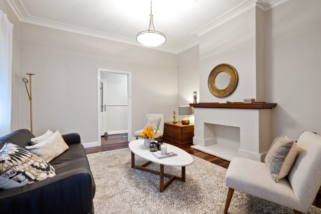 White living room with beige rug, grey chair, black couch and white coffee table