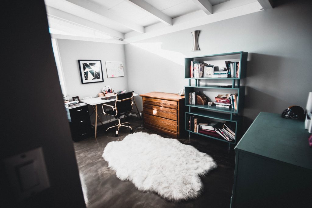 Home office with desk, chair, drawers, bookshelf and white rug