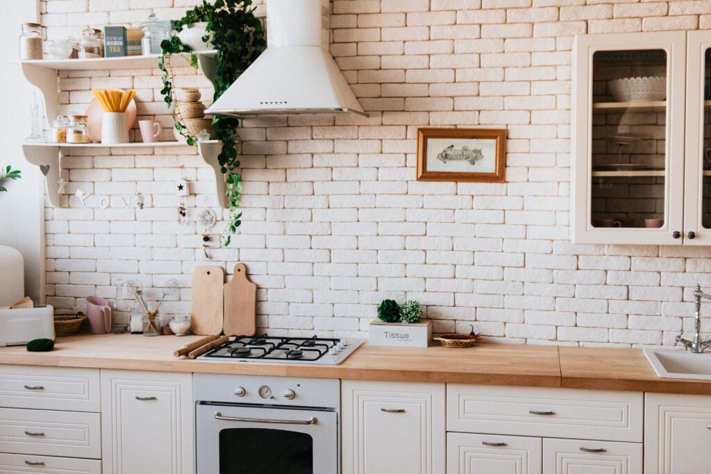 White granny flat kitchen with brick wall and plants