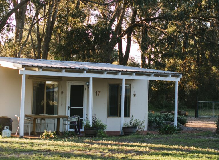 Small, white granny flat with outdoor furniture and lawn