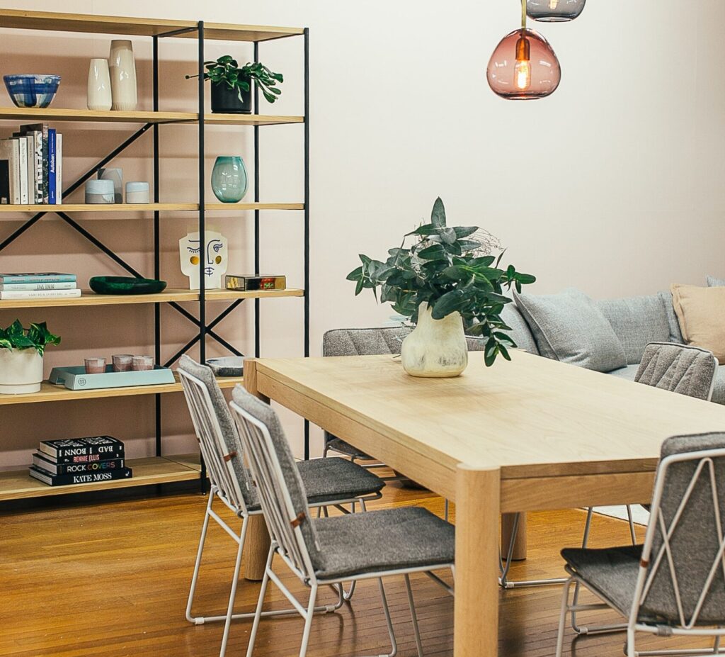 Dining room with wooden table, plant and shelving in the background