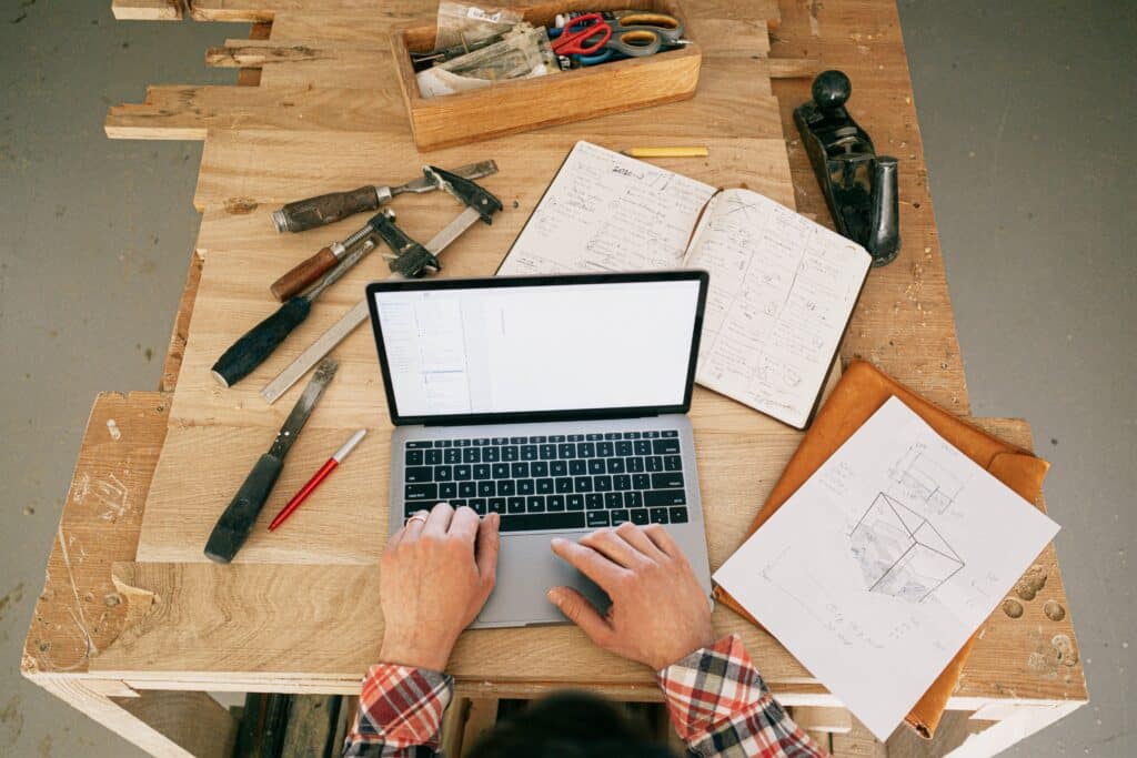 Building materials spread across a work table beside an open laptop.