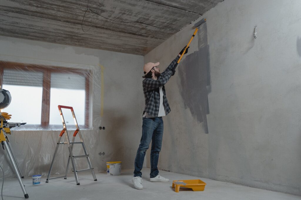 Construction worker applying paint to granny flat interior.