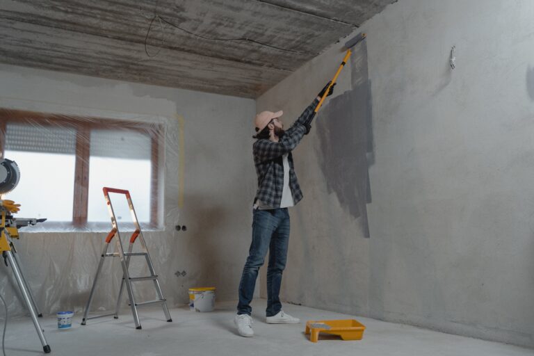 Construction worker applying paint to granny flat interior.